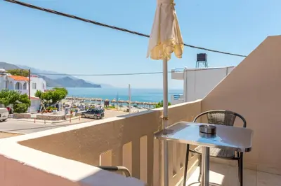 a table on a balcony with a view of the ocean at Nikos Rooms in Palaiochóra