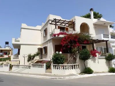 a white house with flowers on the side of it at Alexandra Hotel in Kalamaki Chanion