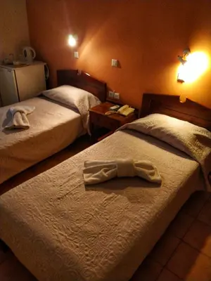 two beds in a hotel room with a robe on the bed at Alexandra Hotel in Kalamaki Chanion