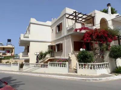 a white house with flowers on the side of a street at Alexandra Hotel in Kalamaki Chanion