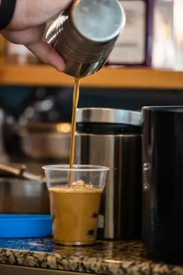 a person pouring a drink into a cup on a counter at Livikon by the Sea in Khóra Sfakíon