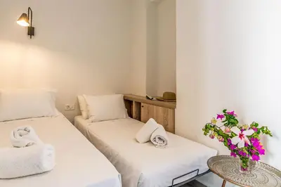 two beds in a room with a vase of flowers at Livikon by the Sea in Khóra Sfakíon