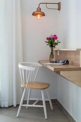 a white chair sitting next to a counter with a vase of flowers at Livikon by the Sea in Khóra Sfakíon