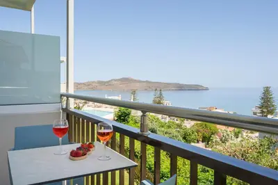 two glasses of wine on a balcony with a view of the ocean at Hermes Sea View in Stalos