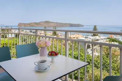a table with a cup of coffee and flowers on a balcony at Hermes Sea View in Stalos