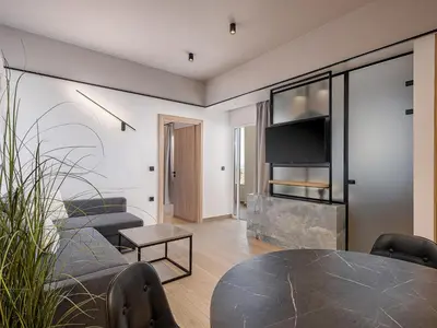 a living room with a table and chairs and a television at Alexia Beach Hotel in Agia Marina Nea Kydonias