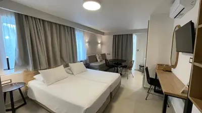 a hotel room with a white bed and a table at Alexia Beach Hotel in Agia Marina Nea Kydonias