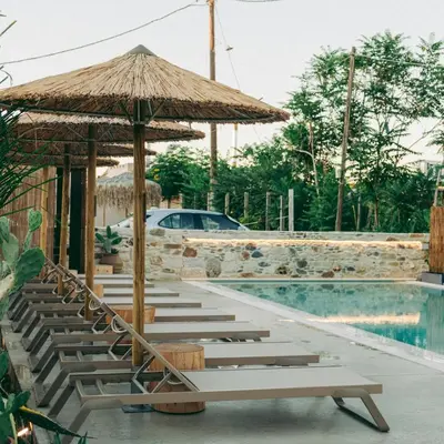 a pool with chairs and umbrellas next to a pool at Miramare Boutique Apartments in Plataniás