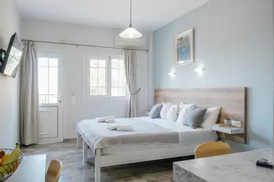 a white bedroom with a large bed and a table at Miramare Boutique Apartments in Plataniás