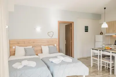 two beds in a room with a kitchen and a table at Miramare Boutique Apartments in Plataniás