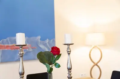 a red rose in a vase on a table with two candles at LOTOS - Luxury Apartments in Kounoupidhianá