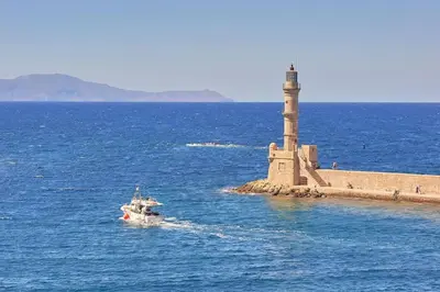 a small boat in the water near a lighthouse at Modern Luxury Studio Near Beach & Old Harbor Fast WiFi Private Veranda in Chania Town