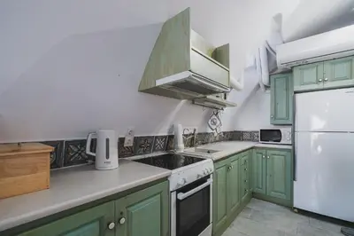 a kitchen with green cabinets and a white refrigerator at Karavos View - An artists' hideaway Paradise in Kalyves