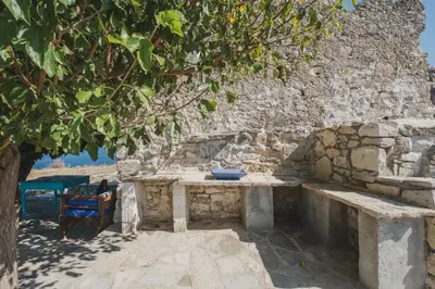 a stone wall with a bench under a tree at Karavos View - An artists' hideaway Paradise in Kalyves