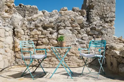 two chairs and a table in front of a stone wall at Karavos View - An artists' hideaway Paradise in Kalyves