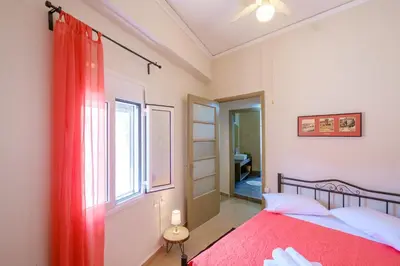 a bedroom with a red bed and a window at Home with Courtyard in Beating Heart of old Town! in Chania Town
