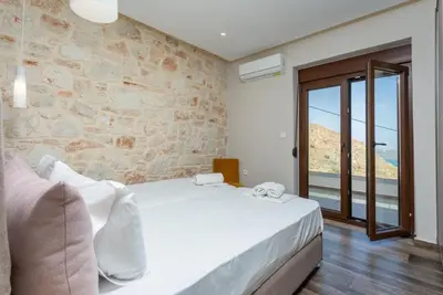 a bedroom with a white bed and a stone wall at Villa Lulla in Beritianá