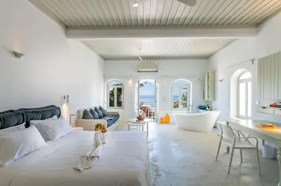 a bedroom with a large white bed and a tub at Samaria by the Sea in Khóra Sfakíon