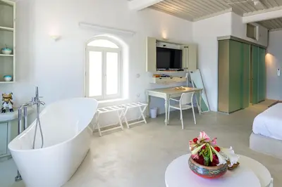 a living room with a tub and a bedroom at Samaria by the Sea in Khóra Sfakíon