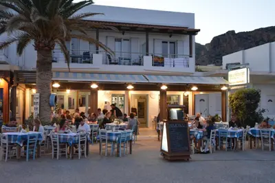 a group of people sitting at tables outside a restaurant at Maria's Hotel in Palaiochóra
