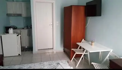 a kitchen with a white table and a white cabinet at Maria's Hotel in Palaiochóra