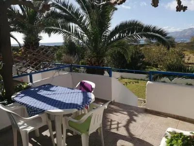 a table and chairs on a balcony with palm trees at Oasis Apartments in Frangokastello