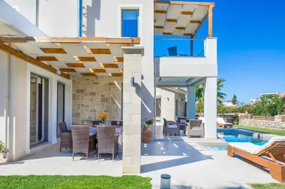 a patio with a table and chairs under a pergola at Villa Alexandros in Nopíyia