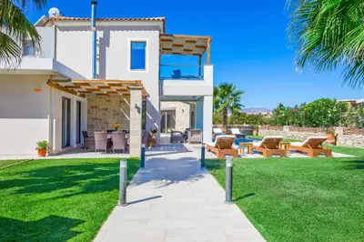 a house with a yard with chairs and a patio at Villa Alexandros in Nopíyia