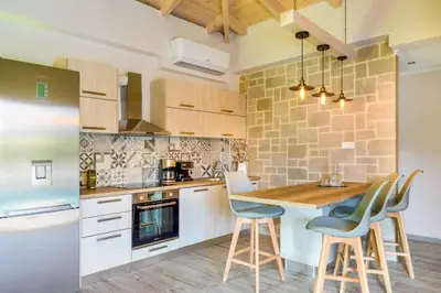 a kitchen with white cabinets and a wooden table and chairs at Villa Elenitsa in Nopíyia