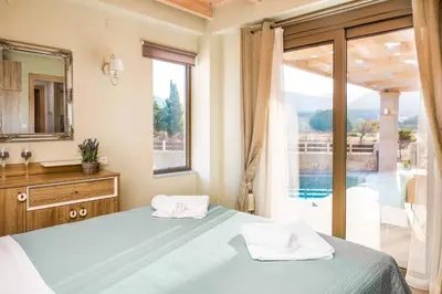 a bedroom with a bed and a view of a pool at Villa Elenitsa in Nopíyia