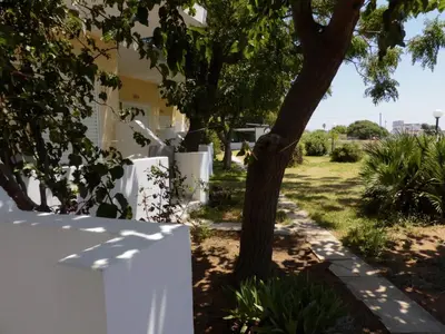 a white fence next to a tree next to a house at Ledakis Studios in Frangokastello
