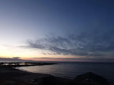a sunset over a body of water with a pier at Vasiliki Apartments in Plataniás