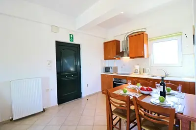 a kitchen with a table and chairs and a black door at Kalimera Apartments in Vamos