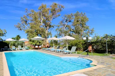 a swimming pool with chairs and umbrellas at Kalimera Apartments in Vamos