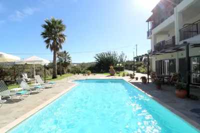 a swimming pool in front of a house at Kalimera Apartments in Vamos