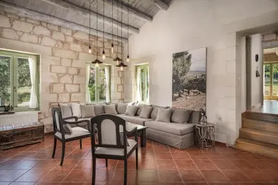 a living room with a couch and a table and chairs at BOUTIQUE VILLA PETRA AMANDA Heated pool optional in Fílippos