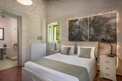 a bedroom with a large white bed in a room at BOUTIQUE VILLA PETRA AMANDA Heated pool optional in Fílippos
