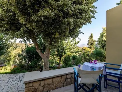 a table and chairs sitting next to a tree at Group Accomodation, Heliopetra Studios And Houses in Douliana