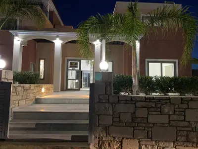 a house with palm trees in front of it at Golden Victory in Agia Marina Nea Kydonias
