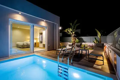 a house with a swimming pool at night at Sarpidon Suites in Agia Marina Nea Kydonias