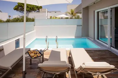 a patio with chairs and a swimming pool at Sarpidon Suites in Agia Marina Nea Kydonias
