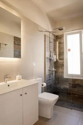a bathroom with a sink and a toilet and a shower at Sarpidon Suites in Agia Marina Nea Kydonias