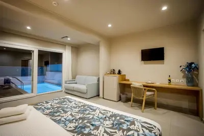 a room with a bed and a desk and a television at Sarpidon Suites in Agia Marina Nea Kydonias