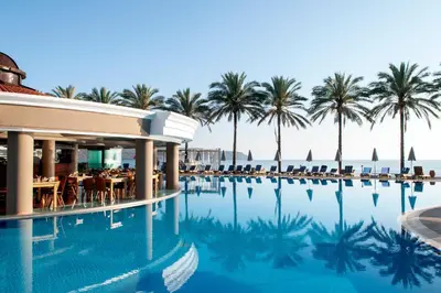 a swimming pool with palm trees in the background at Alexandra Beach Hotel in Agia Marina Nea Kydonias