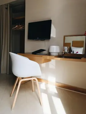 a white chair in a room with a desk and a television at Alexandra Beach Hotel in Agia Marina Nea Kydonias