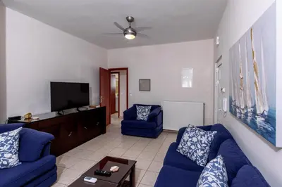 a living room with blue couches and a flat screen tv at Voula's Place in Chania Town