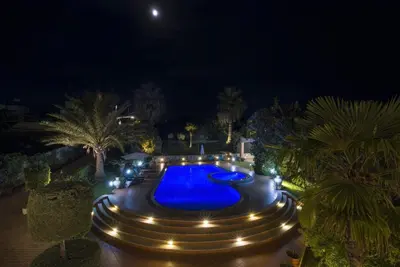 a pool with lights in a yard at night at Villa Elina Luxury Residence in Stalos