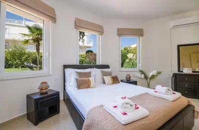 a bedroom with two towels on a bed with windows at Villa Elina Luxury Residence in Stalos