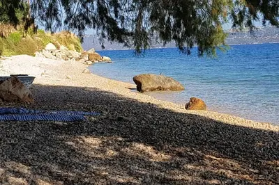 a sandy beach with rocks and the water at Villa Melpomeni in Sinoikismós Plakálona
