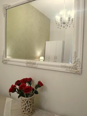 a vase with red roses sitting on a table under a mirror at Meryland in Chania Town